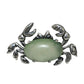 Silver crab-shaped brooch with a green stone on a white background