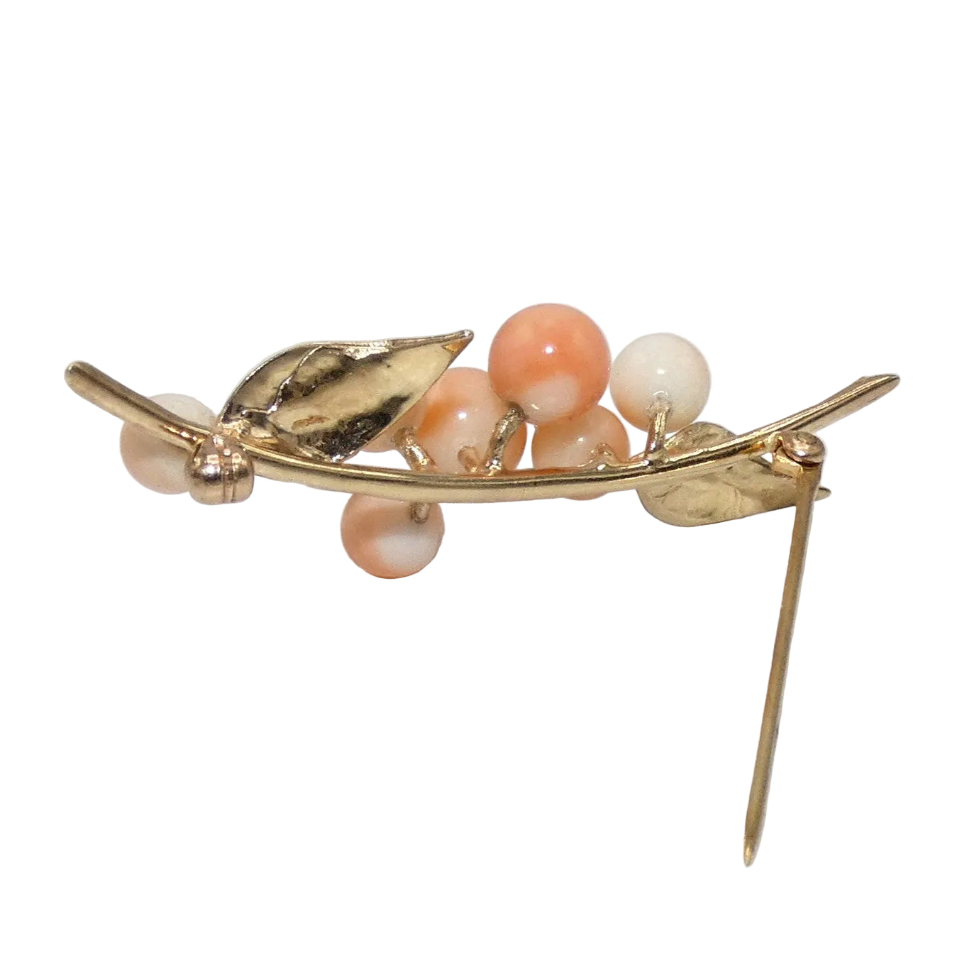 A gold-toned leaf and berry brooch featuring peach and cream colored corals.