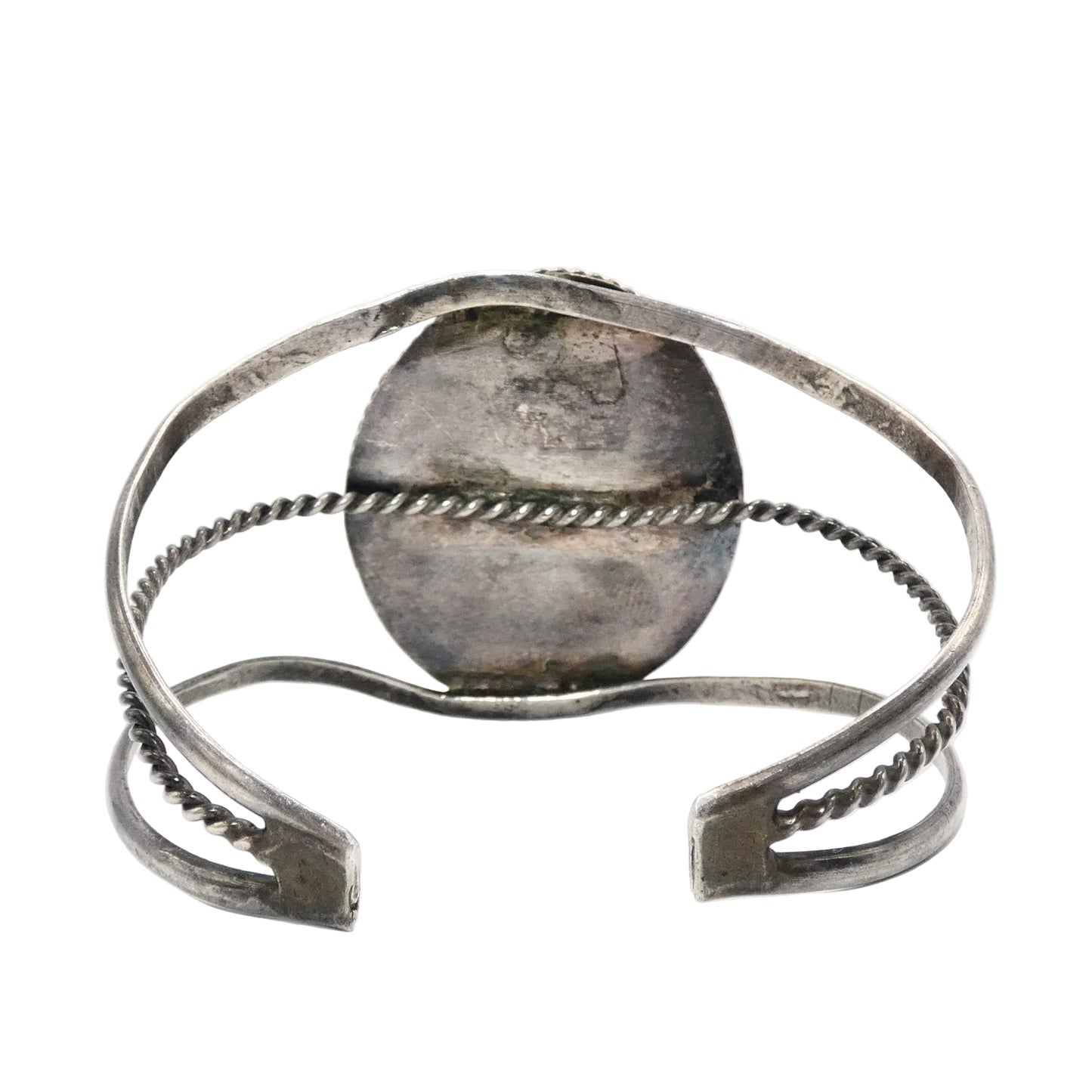 A silver-toned open cuff bracelet with textured twisted wire bands and a flat rectangular end featuring engraved detailing
