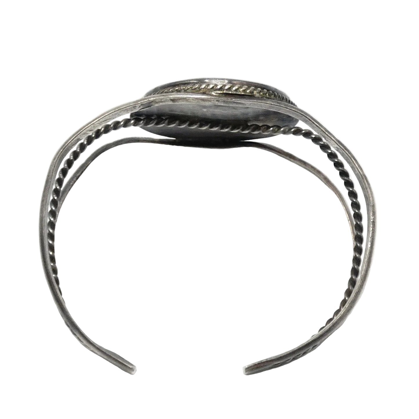 A silver-toned open cuff bracelet with textured twisted wire bands and a flat rectangular end featuring engraved detailing