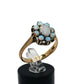 A gold ring featuring a cluster of light blue and white opal gemstones taking the shape of a flower