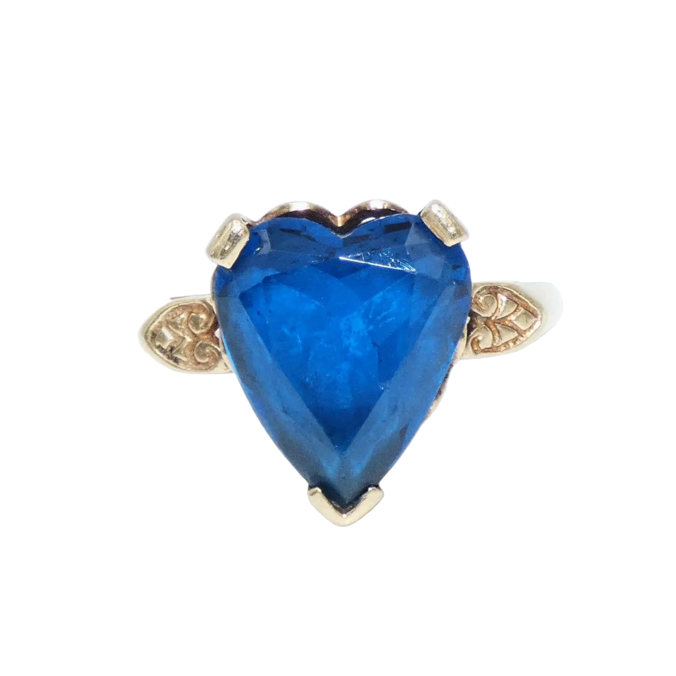 A heart-shaped blue topaz ring set in a 10K gold band with decorative filigree side details in the shape of a heart on both sides