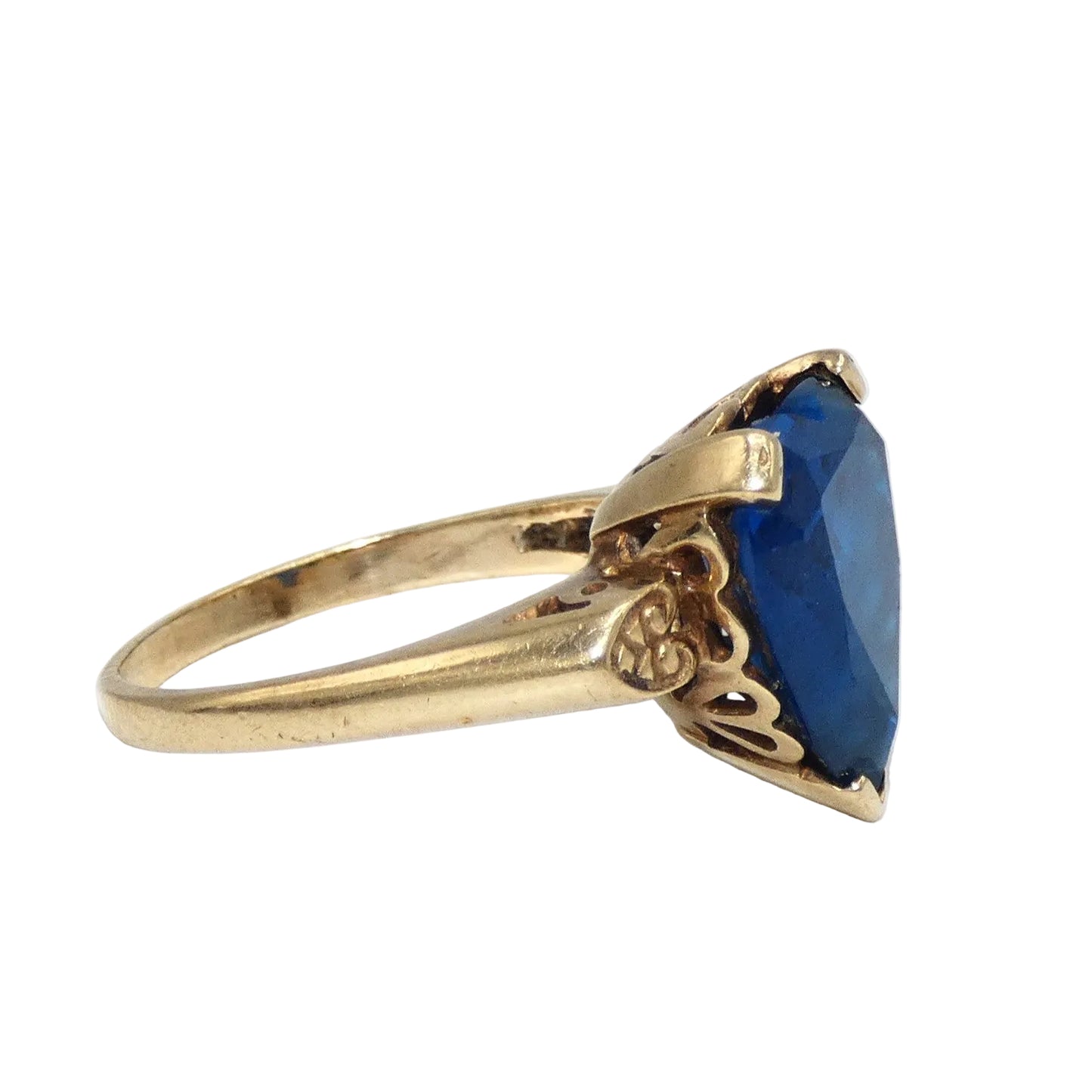 A heart-shaped blue topaz ring set in a 10K gold band with decorative filigree side details in the shape of a heart on both sides