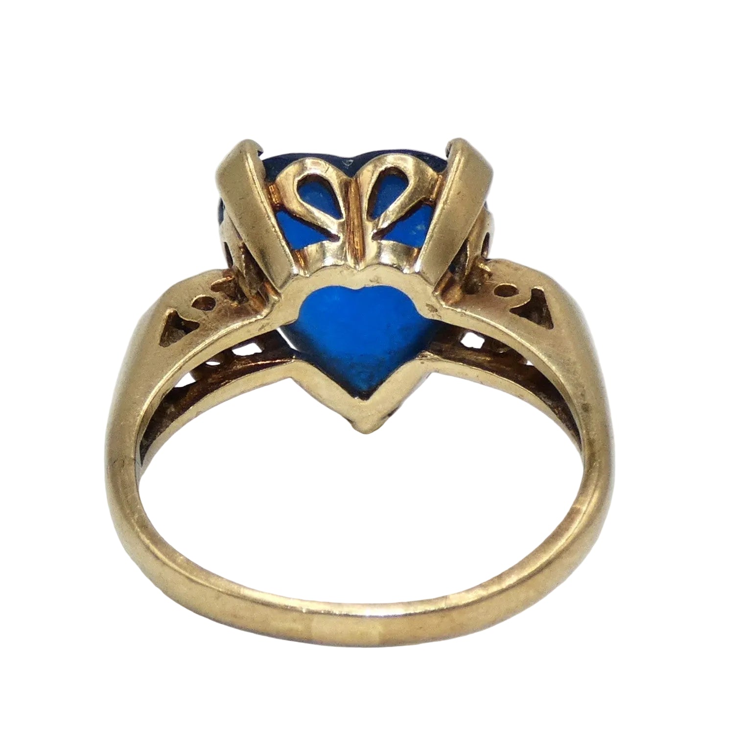 A heart-shaped blue topaz ring set in a 10K gold band with decorative filigree side details in the shape of a heart on both sides