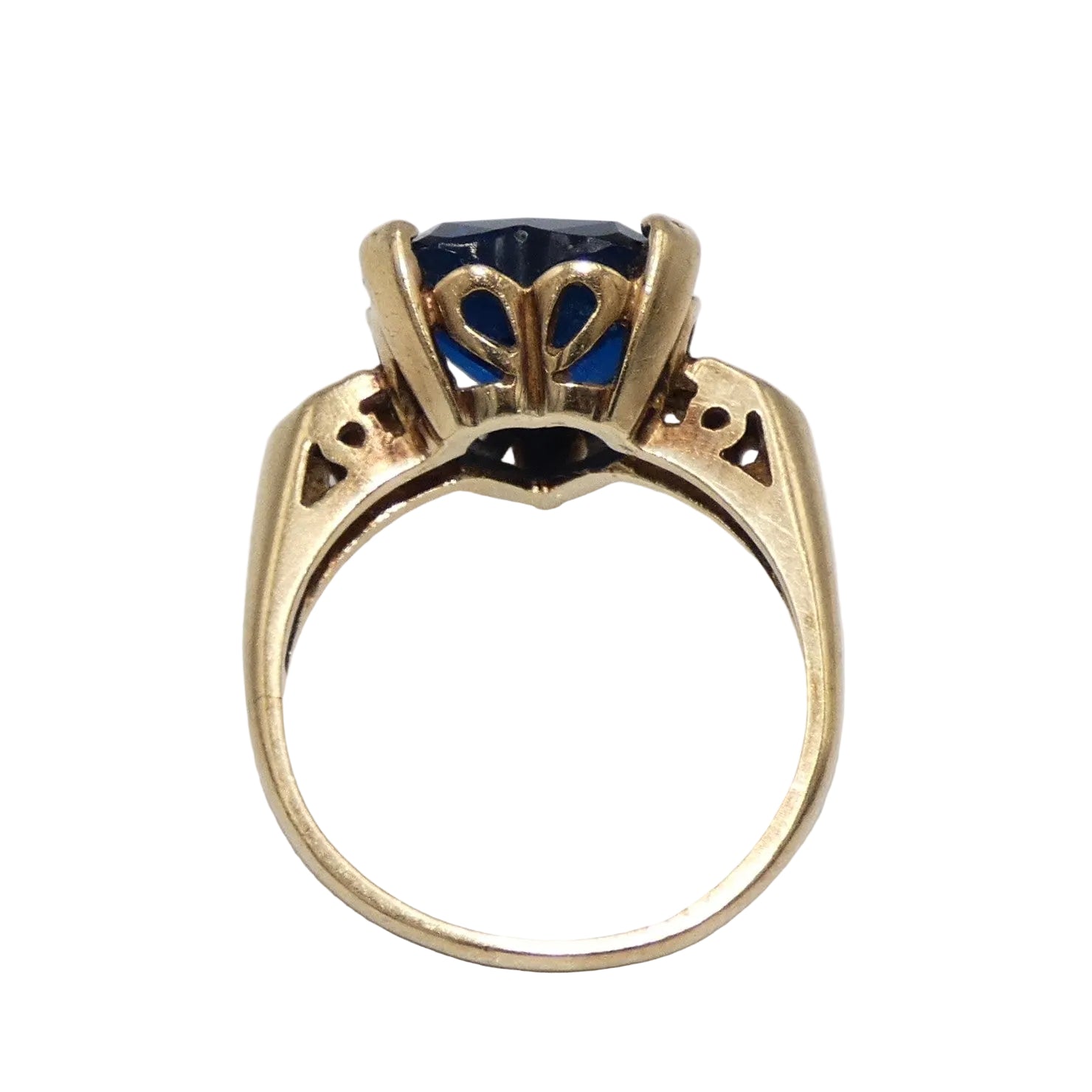 A heart-shaped blue topaz ring set in a 10K gold band with decorative filigree side details in the shape of a heart on both sides