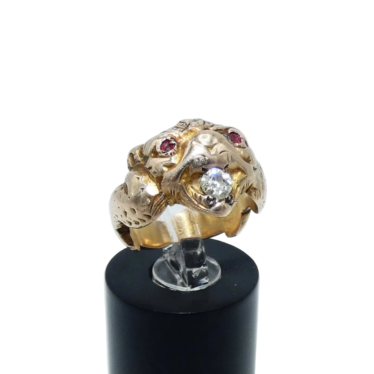 A gold ring shaped like a animal head or creature face, featuring small ruby eyes and a diamond in its mouth