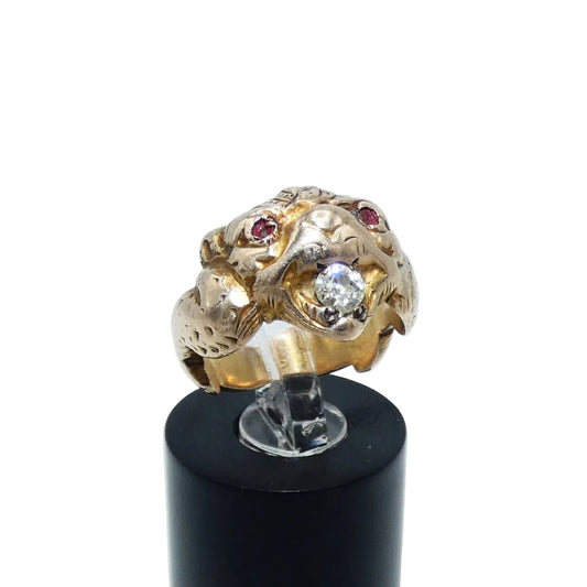 A gold ring shaped like a animal head or creature face, featuring small ruby eyes and a diamond in its mouth