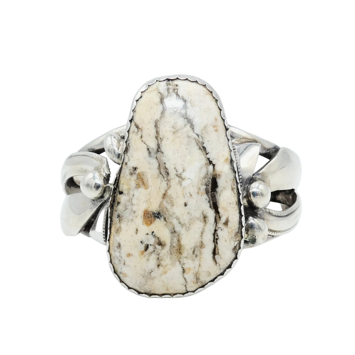  sterling silver cuff featuring awhite buffalo stone cabochon with cream, beige, and brown marbling, set in a polished sterling silver band with decorative leaf-like details