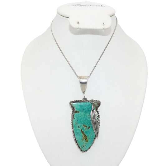 A silver necklace with a turquoise arrowhead pendant and a feather detail